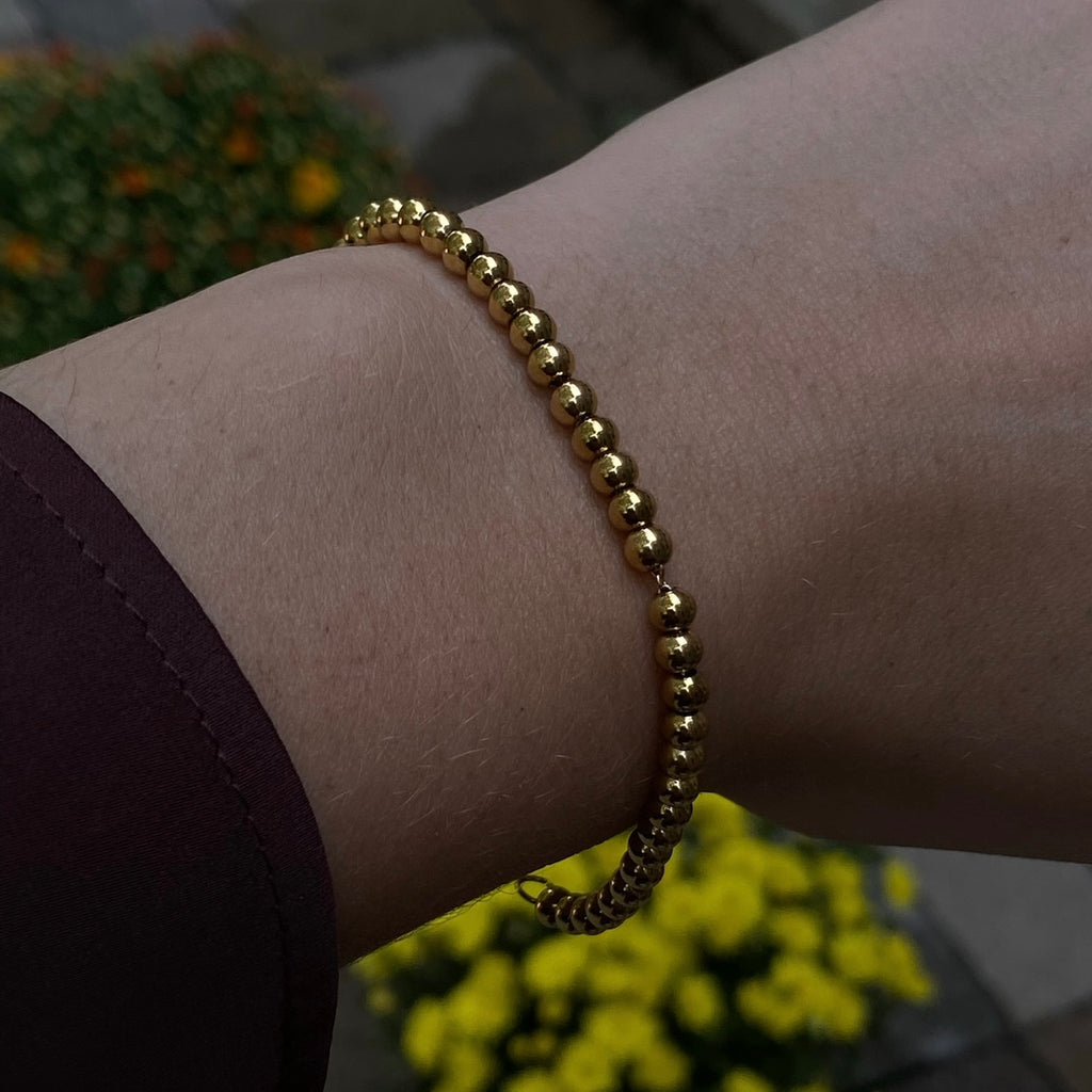 Trendy gold perline bracelet featuring a delicate arrangement of shimmering beads, designed to effortlessly enhance your look with a modern and elegant flair.